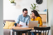 © Tijana - Smiling couple managing finances, reviewing their bank accounts using laptop computer and calculator at modern kitchen stock photo