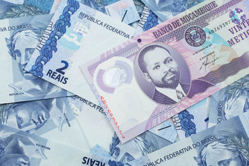 Wall Mural - A close up image of a purple, twenty metical bank note from Mozambique on a background of Brazilian two reais bank notes