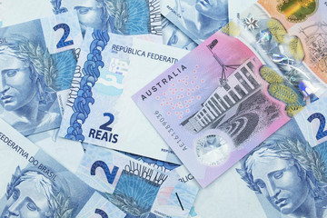 A close up image of an Australian five dollar bill with Brazilian two reais bank notes in macro