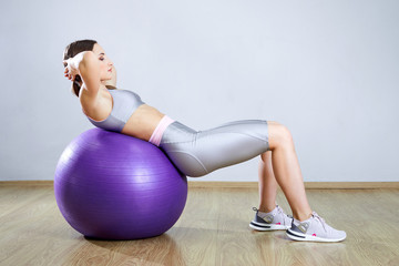 Wall Mural - Young fit woman exercising in a gym. Sports girl is training cross fitness with Pilates Balls.