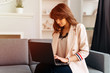 © Iryna - Young beautiful business woman writing in the laptop while at home working due the quarantine