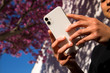 © Cavan Images - woman holding cell phone outdoors in springtime