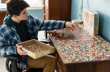 Teen Boy Working On A Jigsaw Puzzle In His Bedroom During Covid 19.