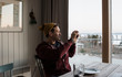 © Cavan Images - man taking pictures of the view from his balcony at home in Sweden