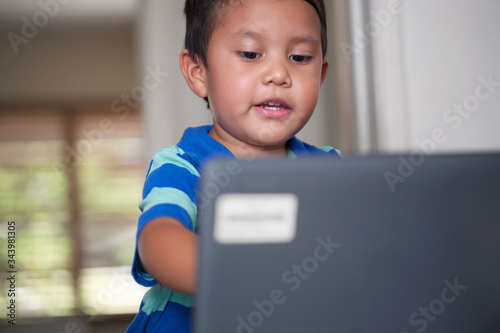 Fotografía A young boy engaged in distance learning class is using a laptop to continue education