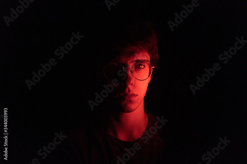 Fotomural Hombre joven en el medio de la oscuridad con la mitad de la cara iluminada por u