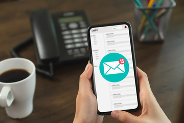 Hand holding smartphone and show email screen on application mobile in the office.