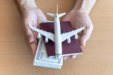 Fototapeta Konie - Man hands holding 100 dollar bills and airplane on wooden table. Travel concept