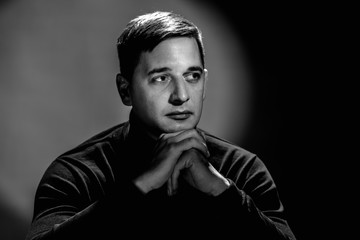 Monochrome studio portrait of serious minded man wearing black clothes