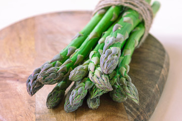 Fresh green asparagus sprouts on a wooden cutboard. Healthy vegan food concept