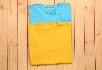 Different stylish t-shirts on wooden background