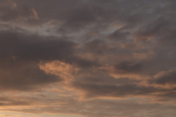 Beautiful evening blue sky at sunset with flaming bright light clouds. A warm summer evening at sunset.