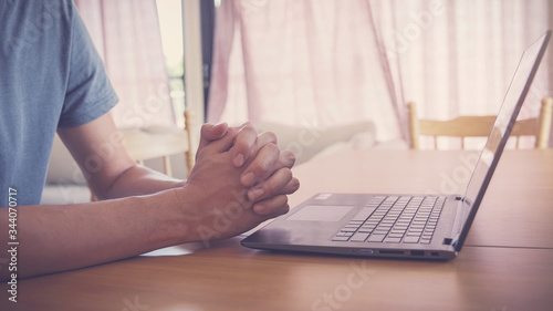 Praying hands with laptop,  worship online at home, streaming online church service, social distancing, new normal  concept
