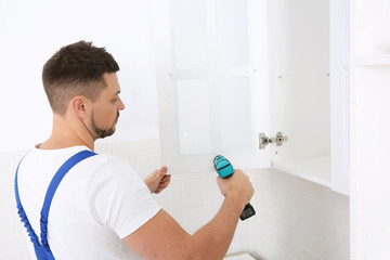 Wall Mural - Worker installing kitchen furniture with electric screwdriver