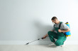 © New Africa - Pest control worker in uniform spraying pesticide indoors. Space for text
