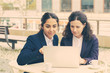 © Mangostar - Businesswomen with laptop in outdoor cafe. Focused female colleagues sitting at table, drinking coffee and using laptop computer in outdoor cafe. Wireless technology concept