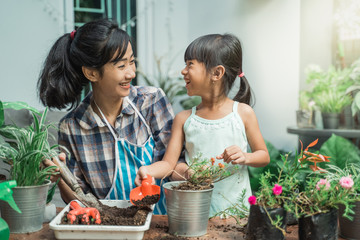 Wall Mural - happy excited mother and her daughter gardening together plants some flower at home