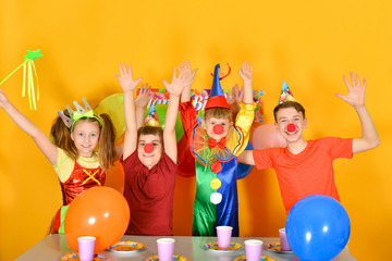 Four children celebrate a birthday with a clown at the table.