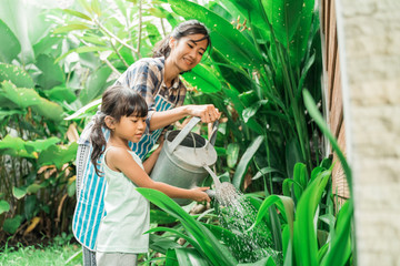 Wall Mural - happy mother and daugther watering her garden together at home