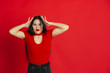 © master1305 - Shocked with head in hands. Caucasian young woman's monochrome portrait isolated on red studio background. Beautiful female brunette model. Concept of human emotions, facial expression, sales, ad.