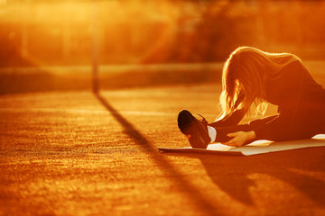 Young athletic woman doing evening  stretching  at the sports stadium. Sunset time.