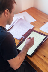 Young university professor is doing online lecture for his students from home during lockdown. He is using 2 in 1 convertible laptop and is writing math formulas with stylus pen