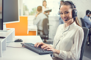 Wall Mural - Portrait of a pretty customer support agent working in the office.