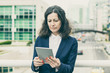 © Mangostar - Focused woman using tablet pc. Serious middle aged businesswoman using digital tablet while standing on urban city street. Wireless technology concept