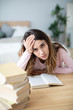 © BestForYou - Sad young woman with books sit at work desk.