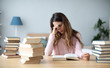 © BestForYou - Sad young woman with books sit at work desk.