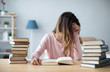 © BestForYou - Female student sits at a table with books preparing for exams.
