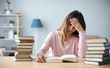 © BestForYou - Sad female student reading a book for the exam or doing homework.