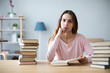 © BestForYou - Female student sits at a table with books preparing for exams.