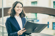 © Mangostar - Cheerful businesswoman holding folder. Smiling middle aged businesswoman in formal wear holding papers and looking aside on street. Professional occupation concept