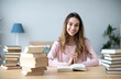 © BestForYou - Female student sits at a table with books preparing for exams.