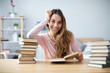 © BestForYou - Portrait of young happy woman sits at a table with books studying at home.