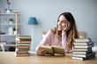 © BestForYou - Portrait of young happy woman sits at a table with books studying at home.