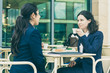 © Mangostar - Businesswomen drinking coffee in outdoor cafe. Female colleagues in formal wear sitting at table and drinking coffee together. Coffee time concept