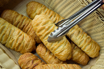 croissant buns from puff pastry on the counter of the bakery department in the store, take the bun with metal tongs