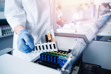 Wall Mural - medical worker in laboratory places blood sample for examination in automatic analyzer. concept dna 