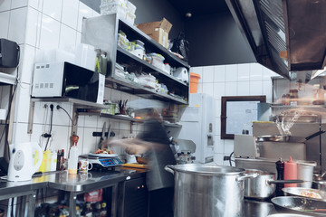 Wall Mural - Behind the scenes of brands. The chef cooking in a professional kitchen of a restaurant meal for client or delivery. Open business from the inside. Meals during the quarantine. Hurrying up, motion.