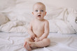 © paralisart - Cute smiling baby sits on the bed. happy naked baby.  children under one year old. baby girl playing, smiling, posing on the bed