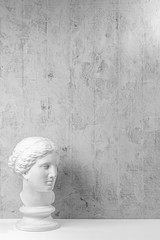 Wall Mural - Mockup with ancient white statue of bust of Venus with grey textured background .Plaster sculpture woman face. The goddess of love in Greek mythology. Renaissance epoch. Copy space.