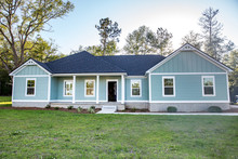 Front View Of A Brand New Construction House With Blue Siding, A Ranch Style Home With A Yard