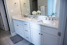 All White And Gray Modern Contemporary Master Bathroom In A Small New Construction House With Tiled Floor, A Vanity Cabinet, Double Sinks And A Mirror