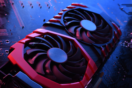 Computer game graphics card, videocard with two coolers on circuit board ,motherboard background. Close-up. With red-blue lighting