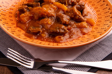 bowl with cooked cassava and meat on wooden table