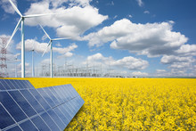 Renewable Or Green Energy Concept With Wind Turbines Solar Panels And Yellow Raps Field On Blue Sky With Clouds