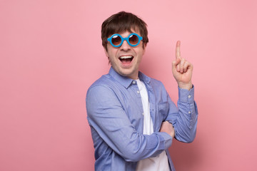 Wall Mural - Young handsome man wearing sunglasses showing finger up, number one.