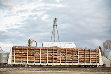A Rail Car Stationed On A Railway Loaded With Rough Cut Logs With An Agriculture Background